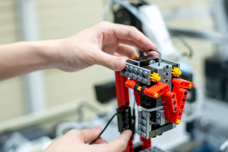 プログラミングやロボット制御の学習に励むエンジニアが赤と灰色の機構パーツを組み立て実践的なメカトロニクス技術を習得している